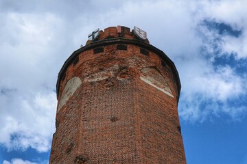 The upper part of the tower of the Teutonic castle in Brodnica against the background of the sky partially covered with white clouds © Grzegorz Sulkowski