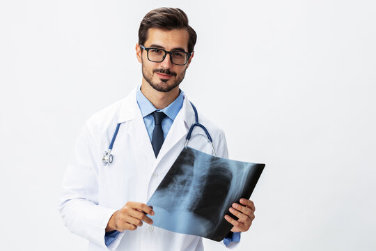 Man doctor in white coat and eyeglasses and stethoscope with a smile looks at patient X-ray images for diagnosis on white isolated background, copy space, space for text, health
