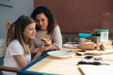 Affectionate mother and daughter eat breakfast together.