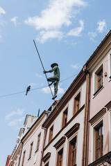 Fototapeta na wymiar Lublin, Poland- May 10, 2023: Sculpture of Rope Walkers at highline at Market Square. Equilibrist or balance master in old town. The view of the statue in the city center on the old street
