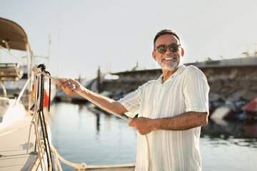 Joyful Mature Man Pulling Rope Docking His Sailboat At Marina