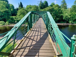 Obraz premium green iron metal and wood foot bridge over water river tees