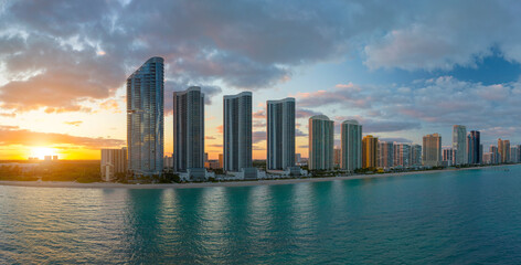 High angle view of Sunny Isles Beach city at sunset with expensive highrise hotels and condo buildings over beachfront on Atlantic shore. American tourism infrastructure in coastal southern Florida