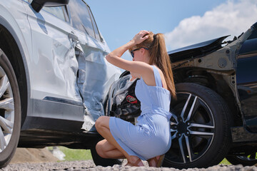 Sad female driver sitting on street side shocked after car accident. Road safety and vehicle...