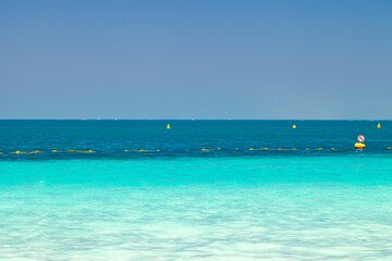 Sea with clear turquoise water and yellow protective buoys in clear day