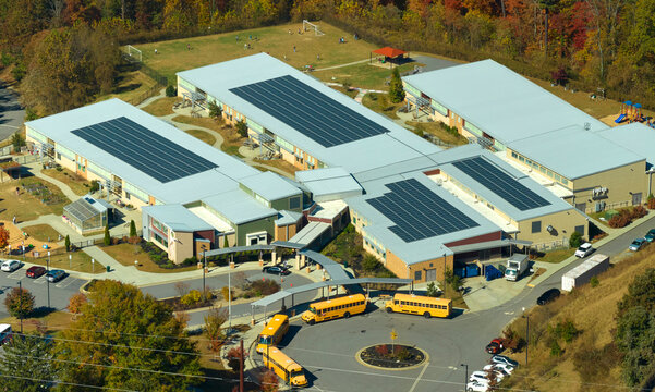 View from above of american school campus with roof covered with photovoltaic solar panels for producing of electrical clean energy