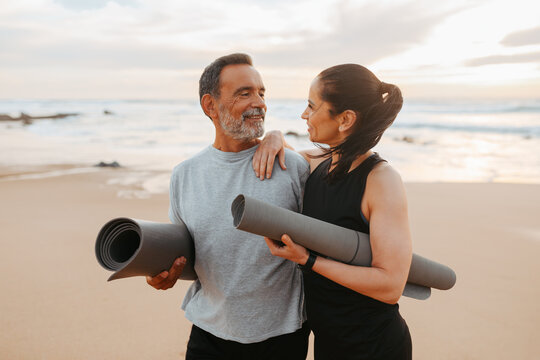 Positive Senior Caucasian Family In Sportswear With Mat Enjoy Workout And Active Lifestyle On Beach In Morning