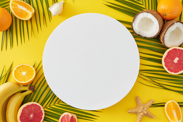 Seaside getaway concept for the summer with a fruity twist. Top view of bananas, coconuts, juicy citrus, seashells, starfish, palm leaves on yellow background with blank circle for advert or text