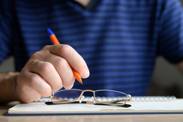 Men's hand holding a ballpoint pen on a planner