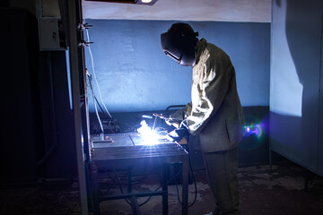 Welder in mask. Metal welding. A bright flash of metal welding