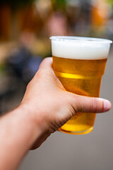 plastic cup glass with beer in hand. Outdoor summer festival