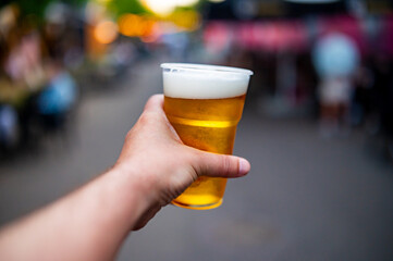 plastic cup glass with beer in hand. Outdoor summer festival