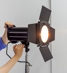 Hand of photographer adjusting, fixing reflector with doors attachment, studio light equipment