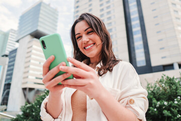 Joyful young lady using a mobile phone to do online shopping or having video call. Entrepreneur woman having fun with her cellphone watching the social media, sending messages or browsing on internet