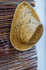 Close-up of shutter bamboo and straw hat indoors, no people.