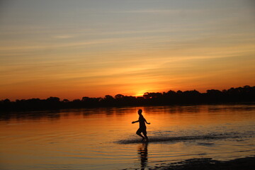 Obraz na płótnie Canvas Silhueta de pessoa não identificada no Pôr do sol no rio araguaia, no Tocantins