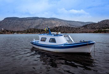 Fototapeta na wymiar A small traditional greek white and blue fishing boat on water in Symi, Greece. 