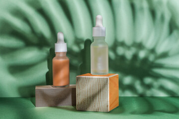 Cosmetic serum bottles on green background monstera shadow