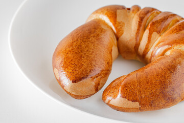 Tasty fresh crescent roll on white board background, selective focus