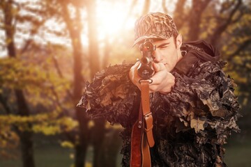 Male hunter hold a gun in forest background