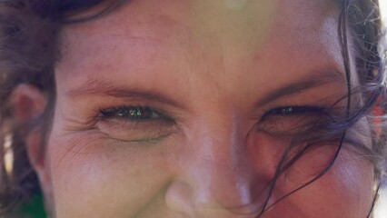 One happy middle-aged woman smiling at camera in macro close-up face and eyes staring hair blows in the wind