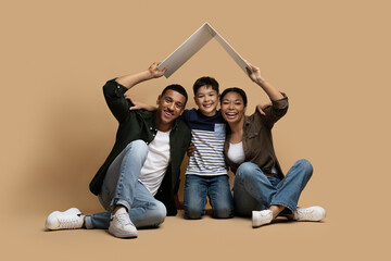 Cute happy multiracial family holding cardboard roof above them