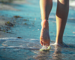 a man walks barefoot along the edge of the beach