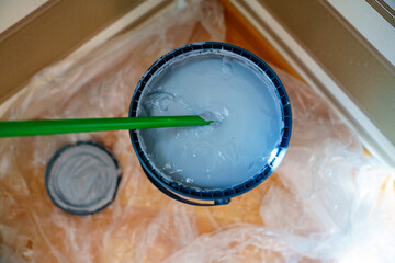 Stirring gray paint in a bucket for high-quality wall painting