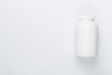 Plastic bottle with vitamins on white background, top view