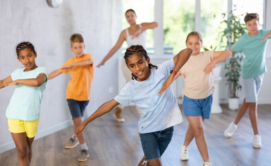 Smiling african american preteen boy dancer practicing active vigorous dance with group in modern studio..