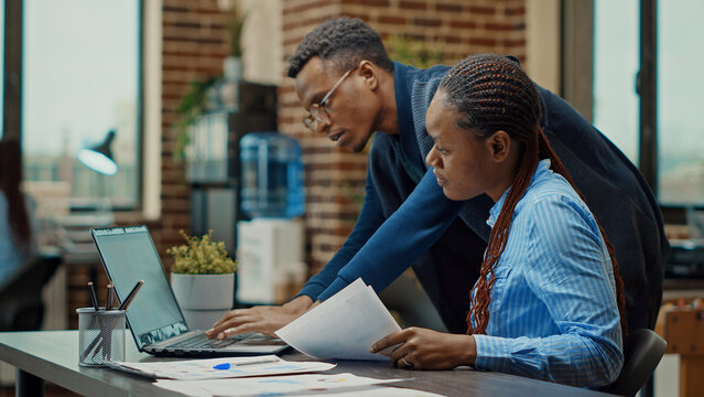 Employees collaborating on new project, reviewing documents for research in office to find new business solutions. Planning analytics reports for development strategy, international startup.