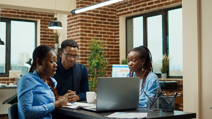 Team of people working on analytics plan with laptop, examining business statistics and results for development. Office employee collaborating on data report presentation, coworking space.