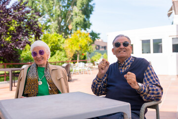 Two seniors dancing in the garden of a nursing home or retirement home at a summer party wearing...