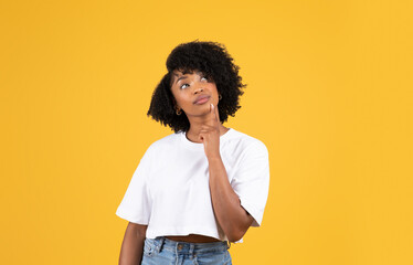Pensive positive millennial black lady in casual, thinking, look at copy space