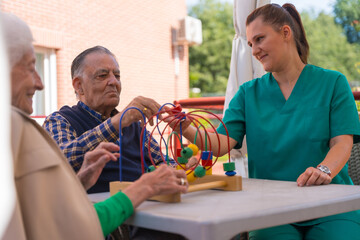 Two elderly people in the garden of a nursing home or retirement home playing with games to improve the mobility of the hands