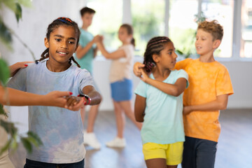 Active young multinational children enjoying of partner dance in in dance studio