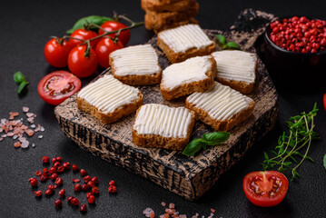 Delicious salty rectangular wheat croutons with cream cheese and tomatoes