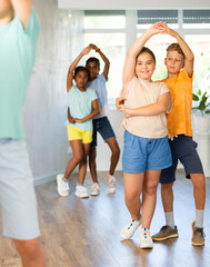 Active preteen children practicing Ballroom dances in pairs in training hall during dancing classes