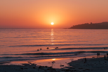 Sunset on the sea with surfers in Carmel, California