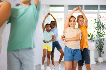 Interested modern tweens, girl and boy learning to dance waltz as couple in children choreographic...