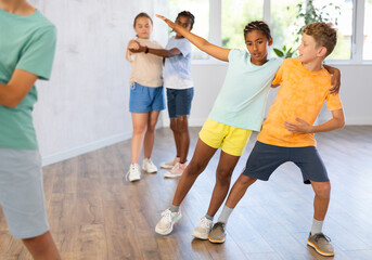 Fototapeta premium Positive tweenagers, boy and girl dancing together slow ballroom dances in pair during group children choreography lesson ..