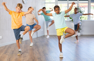 Fototapeta na wymiar Dynamic little boys and girls attendees of dancing courses training Break-dance poses in dancehall