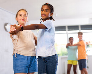 Happy multinational boys and girls enjoying active dance in studio
