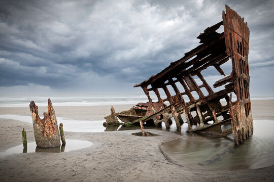 Rusted old shipwreck on sandy beach 