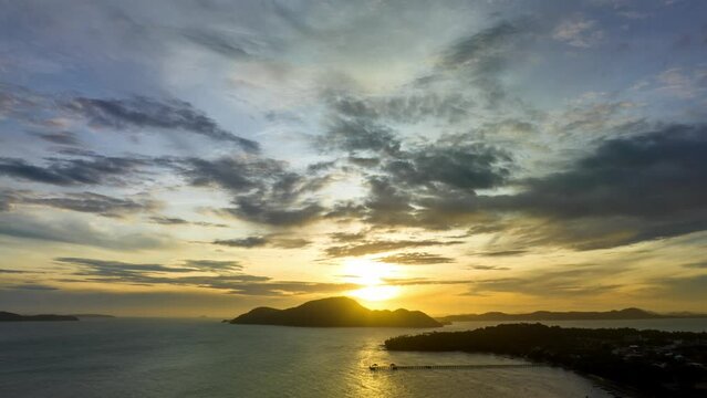 Aerial Hyperlapse view clouds moving in yellow sky at sunrise moving slowly above islands at Rawai beach Phuket. Nature video High quality footage. Scene of yellow sunrise with cloud background.