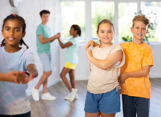 Obraz premium Light-skinned boy and girl dance in pairs and rehearse dance before performing on main floor. Classes for children workout in mini group gym