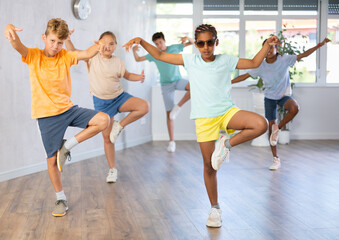 Fototapeta na wymiar Positive cheerful smiling children studying modern style dance in class indoors