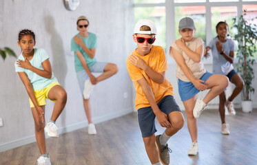 Obraz premium Smiling girls and boys doing dance workout during group class in fitness center