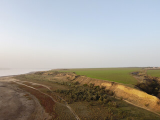 a plowed field and a rugged shore with trees and rural road