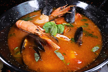 Seafood soup with mussels and shrimps in black bowl - 619607361